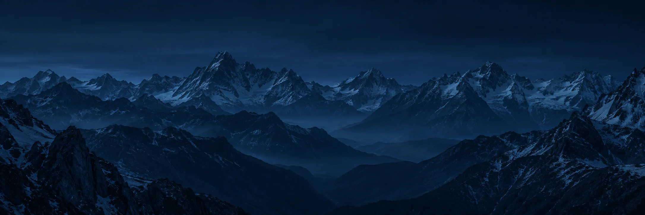 Dunkle Berggipfel unter einem blauen Nachthimmel.